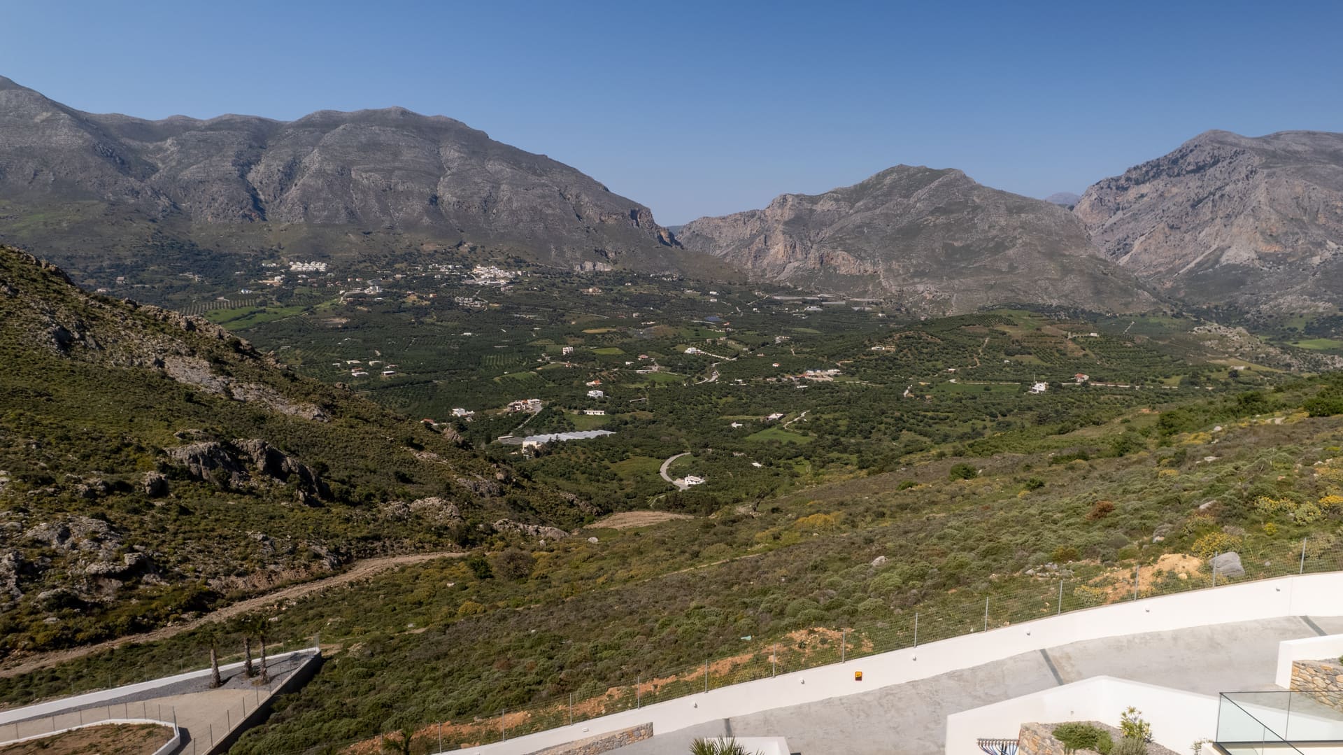 Drone view inland over the mountain valley and village with the villa terrace in the foreground