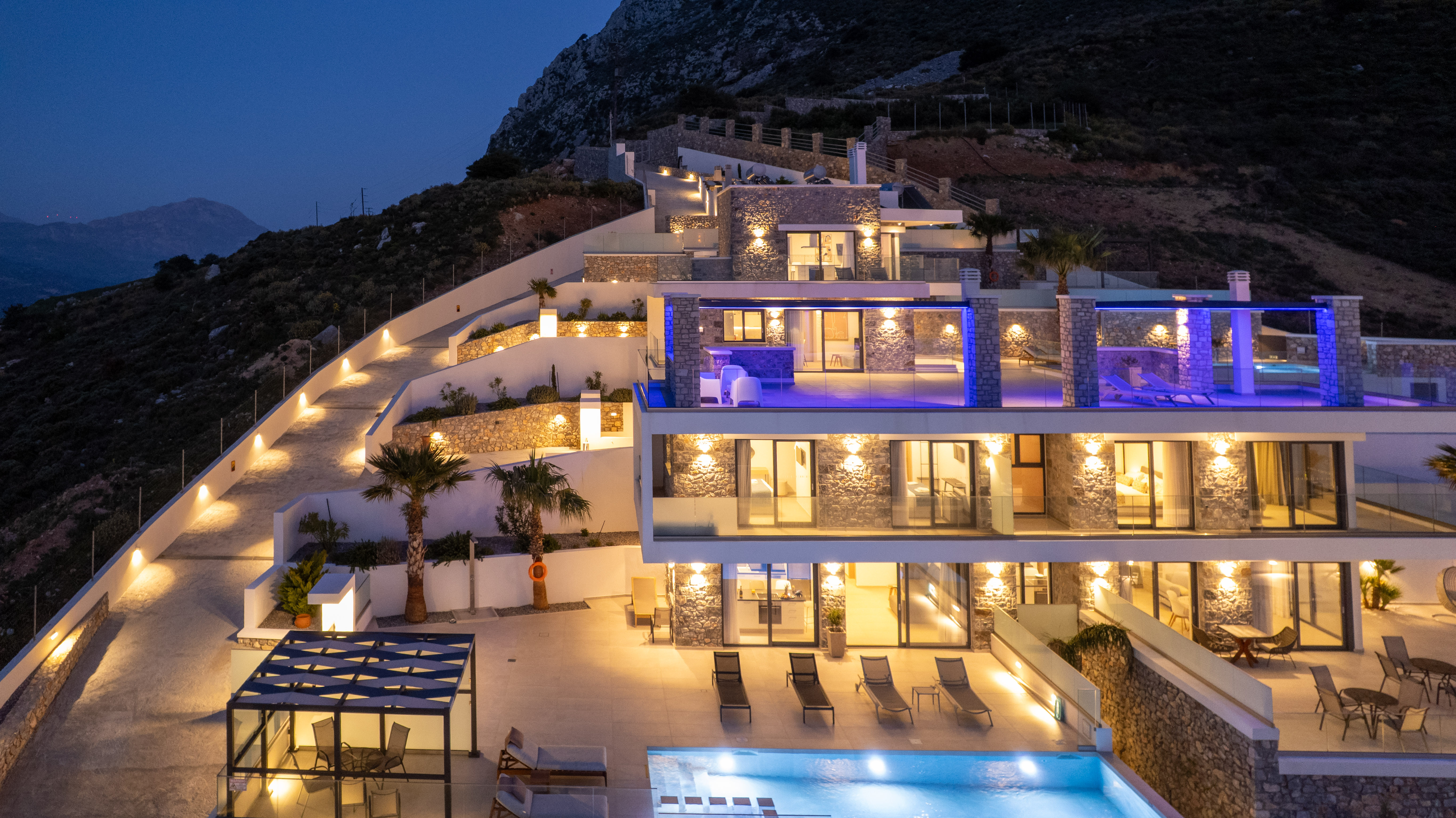 Secret Oasis estate at night — illuminated pool, terraces and palms above Plakias, South Crete